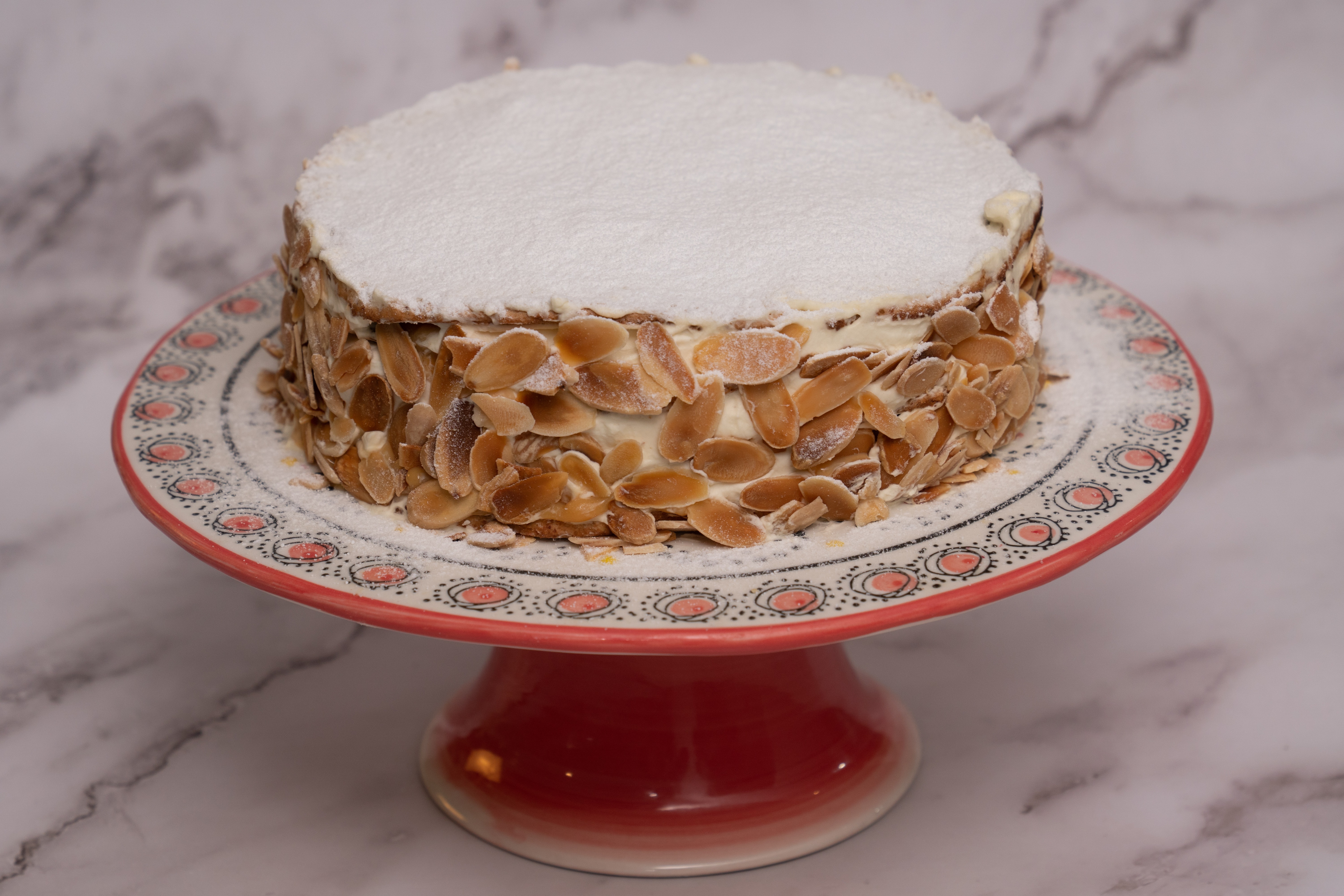 Torta merengue de almendras, crema, manjar y frambuesa